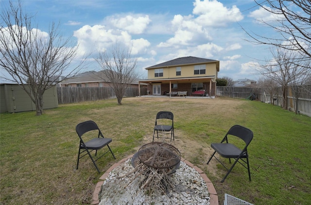 back of house featuring a lawn, a patio, and an outdoor fire pit