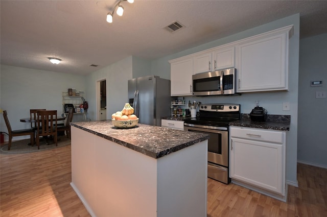 kitchen featuring white cabinetry, a center island, stainless steel appliances, a textured ceiling, and light hardwood / wood-style flooring