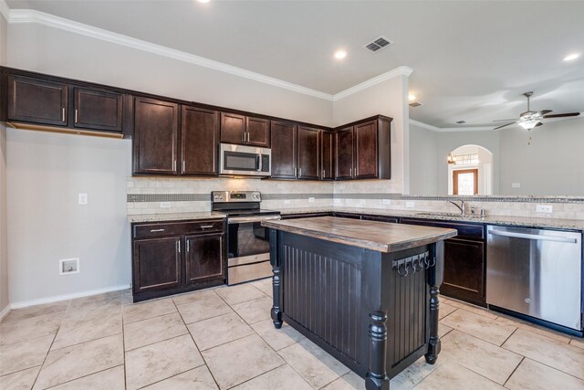 kitchen with sink, tasteful backsplash, vaulted ceiling, light tile patterned floors, and appliances with stainless steel finishes