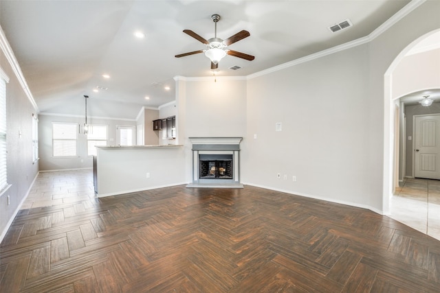 unfurnished living room with dark parquet flooring, vaulted ceiling, ceiling fan, and crown molding