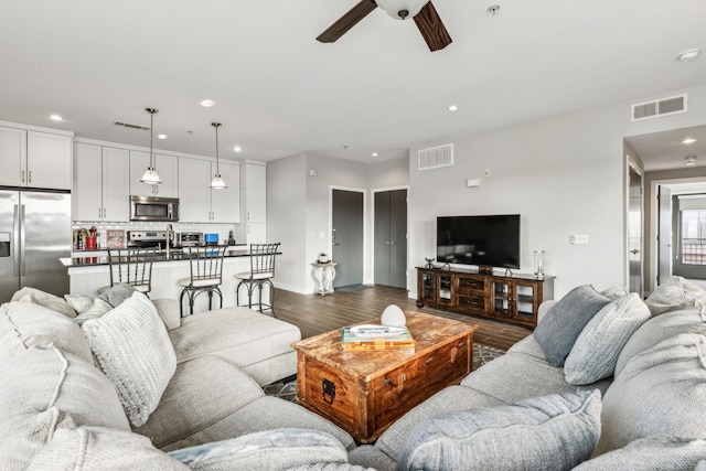 living room with ceiling fan and dark hardwood / wood-style flooring