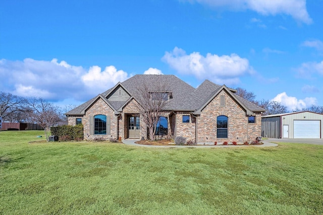 french country inspired facade featuring a garage, an outdoor structure, and a front yard