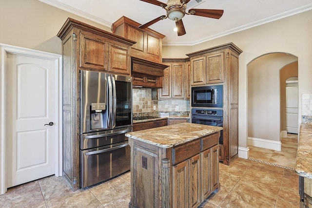 kitchen featuring light stone counters, black appliances, ornamental molding, a kitchen island, and backsplash