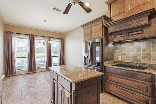 kitchen with ornamental molding, a center island, stainless steel fridge, and black electric cooktop