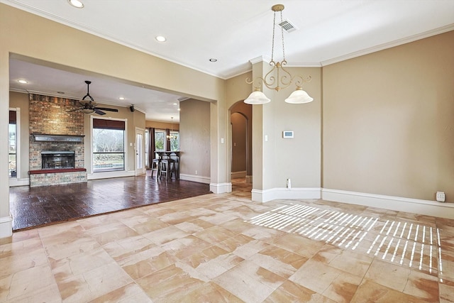 interior space with ceiling fan, ornamental molding, a fireplace, and hanging light fixtures