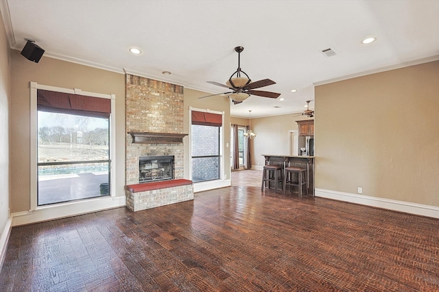 unfurnished living room with crown molding, a brick fireplace, dark hardwood / wood-style floors, and ceiling fan