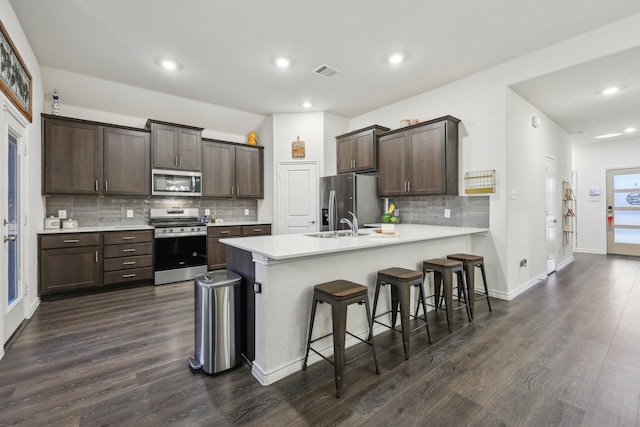 kitchen with stainless steel appliances, dark wood-type flooring, a kitchen bar, and kitchen peninsula