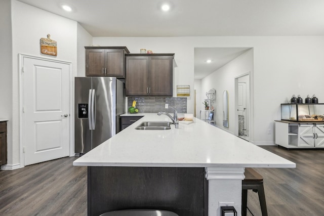 kitchen featuring stainless steel refrigerator with ice dispenser, a breakfast bar, sink, dark brown cabinets, and dark hardwood / wood-style flooring