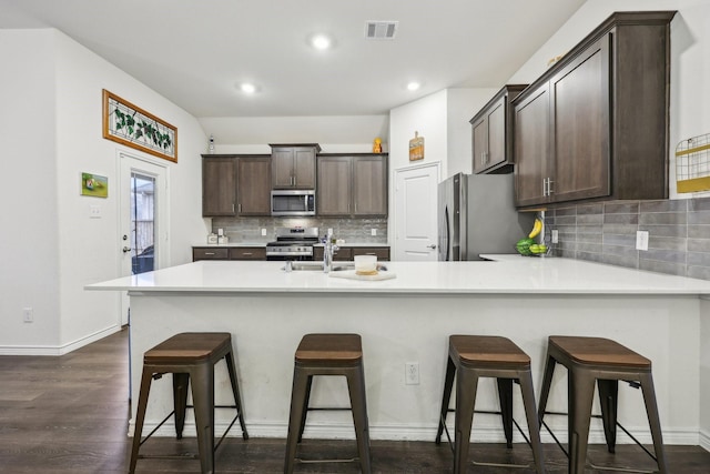 kitchen with appliances with stainless steel finishes, a breakfast bar, sink, and dark brown cabinets