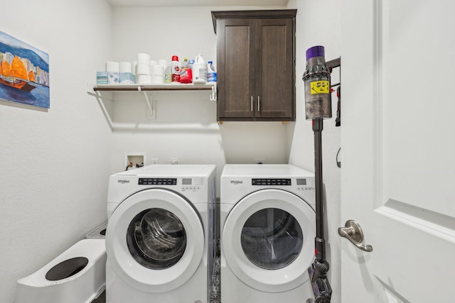 clothes washing area with cabinets and washing machine and clothes dryer