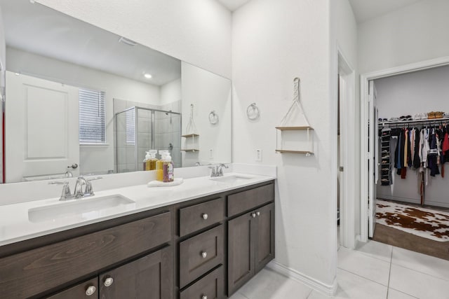 bathroom with a shower with door, vanity, and tile patterned floors