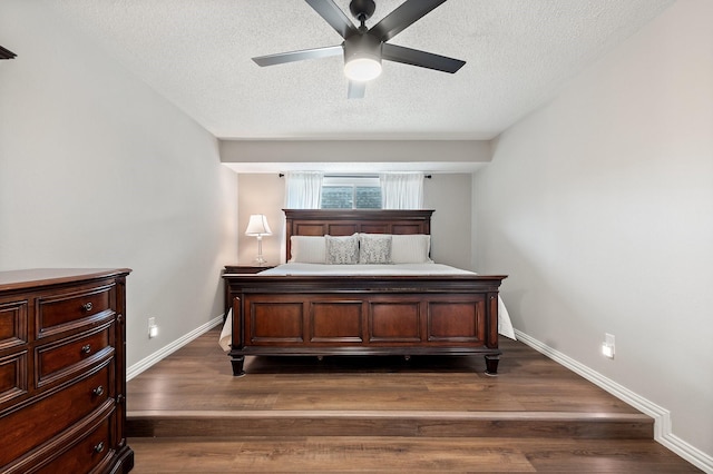 bedroom with ceiling fan, a textured ceiling, and dark hardwood / wood-style flooring