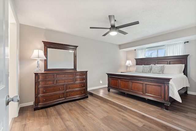 bedroom featuring hardwood / wood-style flooring, a textured ceiling, and ceiling fan