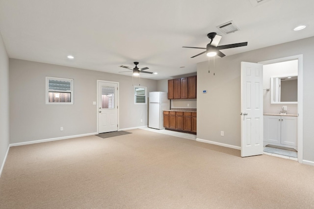 unfurnished living room with sink, light carpet, and ceiling fan