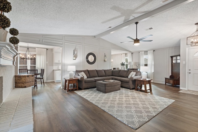 living room with ceiling fan with notable chandelier, hardwood / wood-style floors, a textured ceiling, and vaulted ceiling with beams