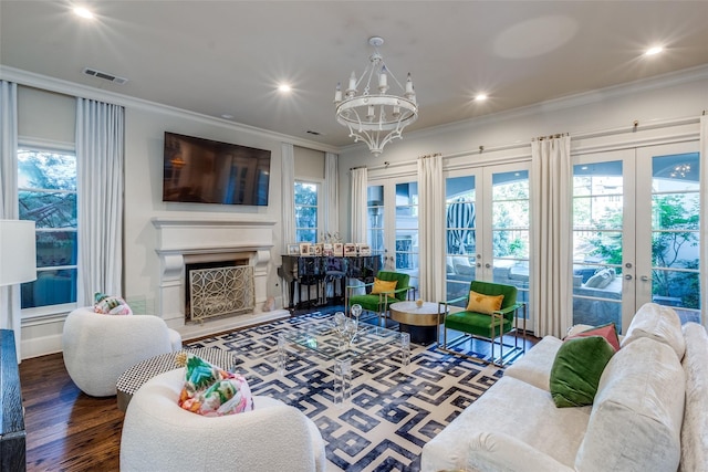 living room with an inviting chandelier, crown molding, wood-type flooring, and french doors