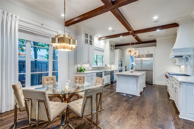 kitchen with an island with sink, white cabinetry, hanging light fixtures, custom exhaust hood, and stainless steel appliances