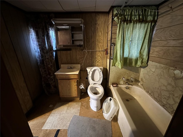 bathroom with toilet, vanity, wooden walls, and a bath