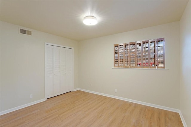 unfurnished bedroom with light wood-type flooring and a closet