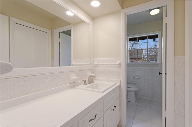 bathroom with tile walls, vanity, tile patterned flooring, and toilet