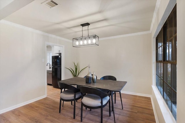 dining room with crown molding and light wood-type flooring