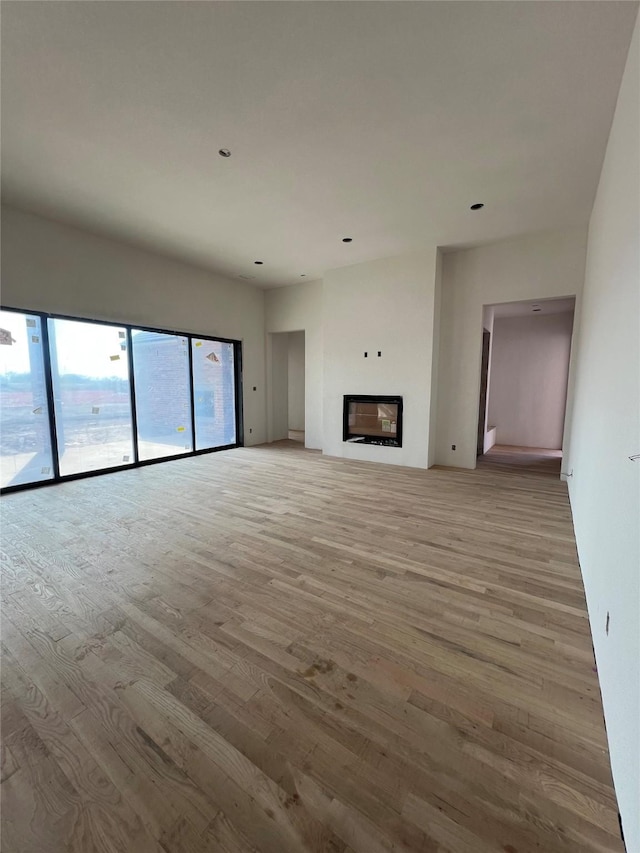 unfurnished living room with a glass covered fireplace and light wood-style flooring