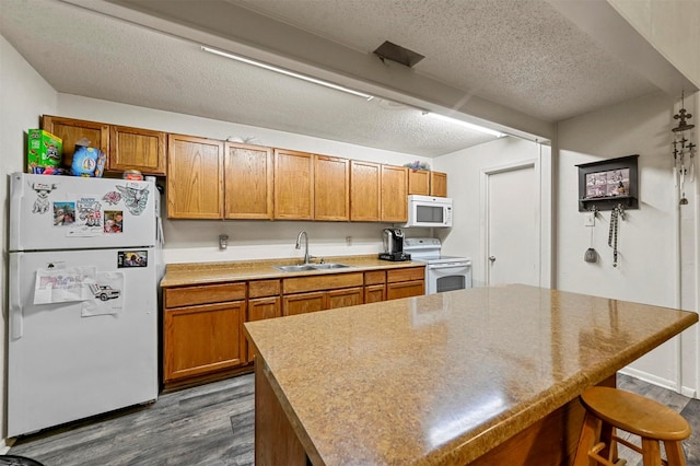 kitchen featuring dark hardwood / wood-style flooring, sink, white appliances, and a center island