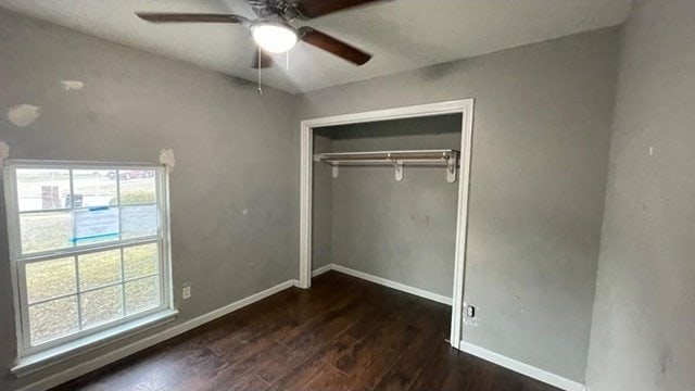 unfurnished bedroom with multiple windows, dark hardwood / wood-style flooring, ceiling fan, and a closet