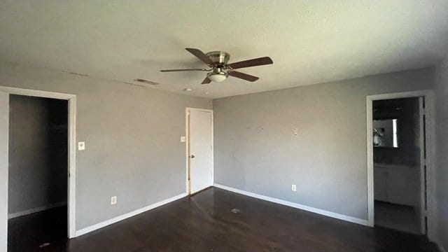 unfurnished bedroom featuring dark hardwood / wood-style flooring, a walk in closet, and ceiling fan