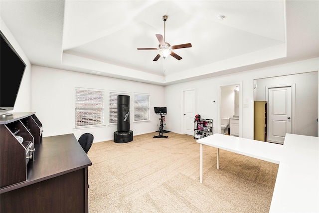 workout room with a tray ceiling, carpet floors, and ceiling fan