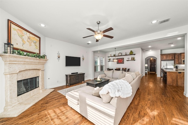 living room featuring wood-type flooring, ceiling fan, and a high end fireplace