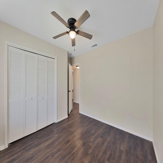 unfurnished bedroom with dark wood-type flooring, a closet, and ceiling fan