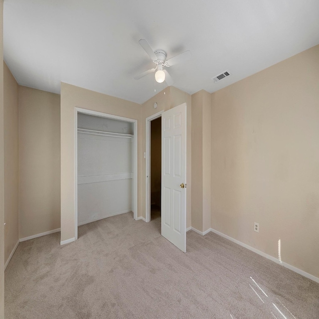 unfurnished bedroom featuring light colored carpet, a closet, and ceiling fan