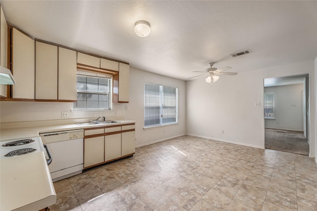 kitchen featuring dishwasher, sink, ceiling fan, cream cabinets, and a textured ceiling