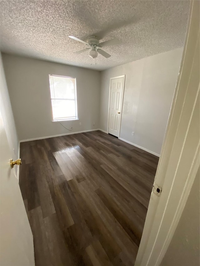 spare room with ceiling fan, dark wood-type flooring, and a textured ceiling