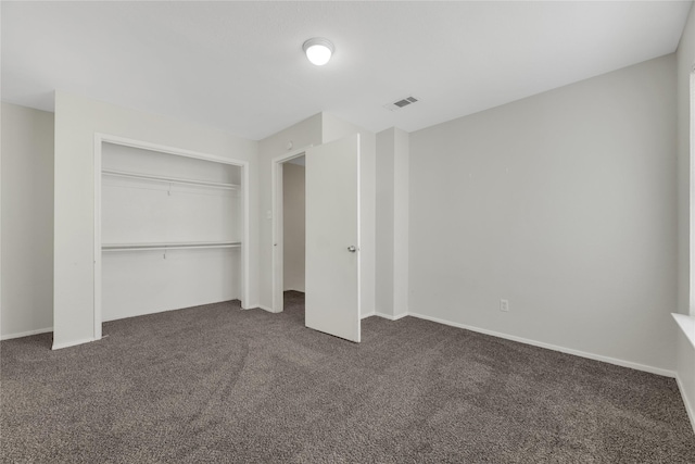 unfurnished bedroom with dark carpet and a closet