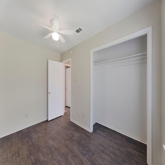 unfurnished bedroom featuring dark hardwood / wood-style flooring, ceiling fan, and a closet