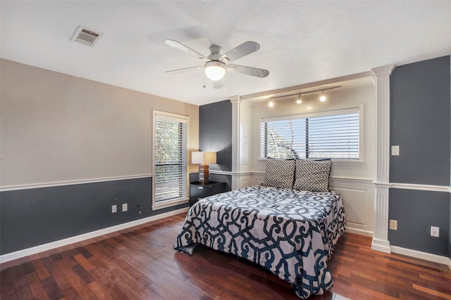 bedroom featuring a textured ceiling, dark hardwood / wood-style floors, ceiling fan, and ornate columns