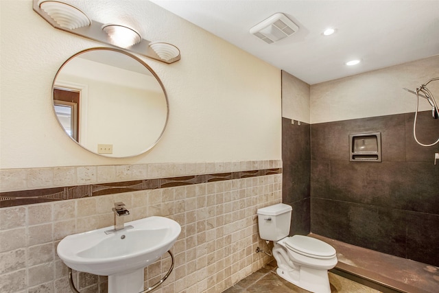 bathroom with a shower, sink, tile walls, toilet, and tile patterned floors