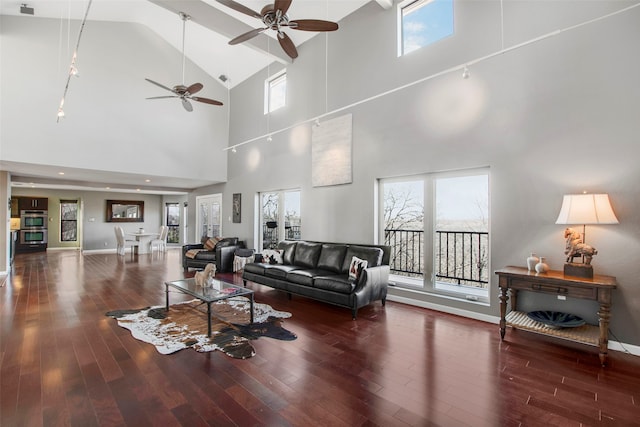 living room with dark wood-type flooring, ceiling fan, and a high ceiling