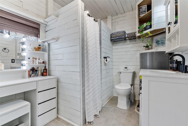 bathroom with tile patterned flooring, vanity, wood walls, and toilet