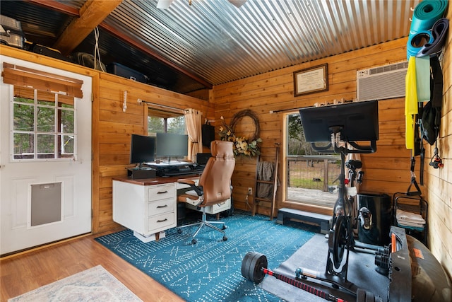 home office featuring hardwood / wood-style flooring, vaulted ceiling, a wall unit AC, and wooden walls