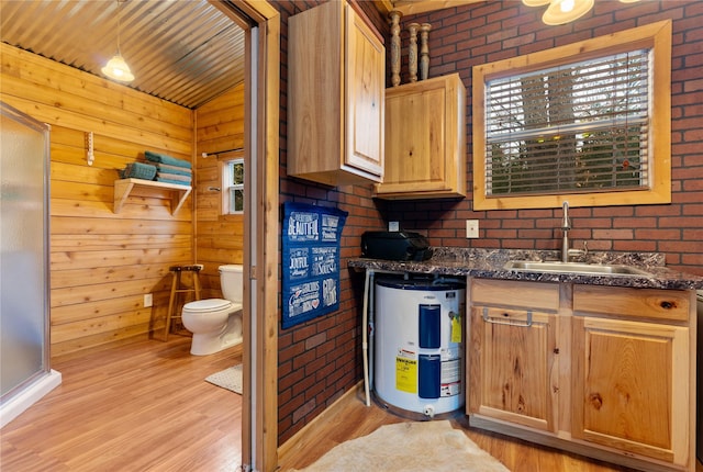 kitchen with brick wall, light hardwood / wood-style floors, sink, and water heater