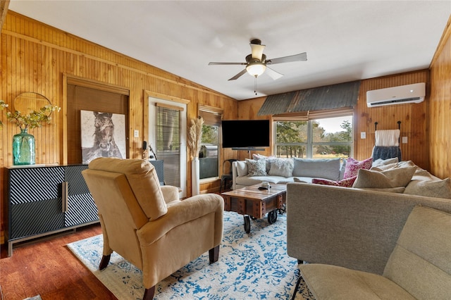 living room featuring an AC wall unit, ceiling fan, and wood walls