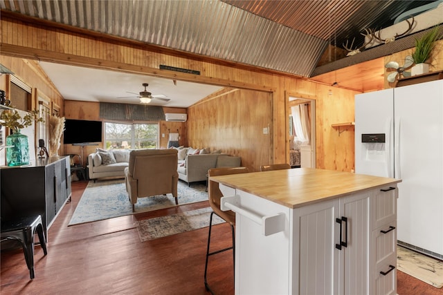 kitchen featuring wood counters, wood walls, white cabinetry, a center island, and white fridge with ice dispenser