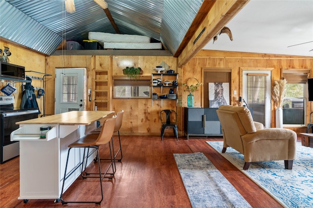 kitchen featuring dark hardwood / wood-style floors, vaulted ceiling with beams, a kitchen breakfast bar, ceiling fan, and stainless steel appliances