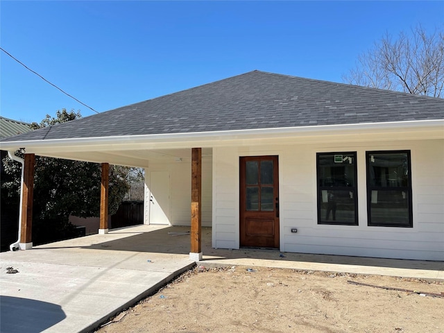 exterior space with driveway and roof with shingles