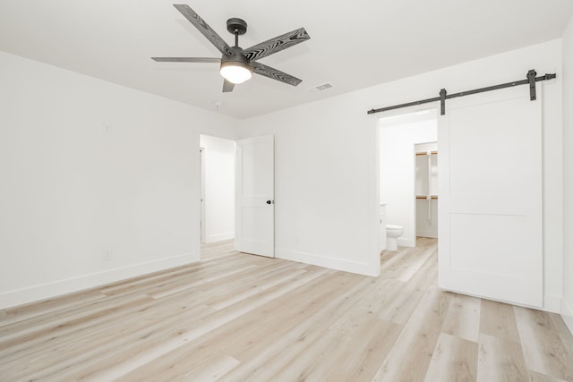 308 Santa Fe, Wolfe City, TX 75496 - unfurnished bedroom featuring baseboards, a barn door, light wood-style flooring, and visible vents