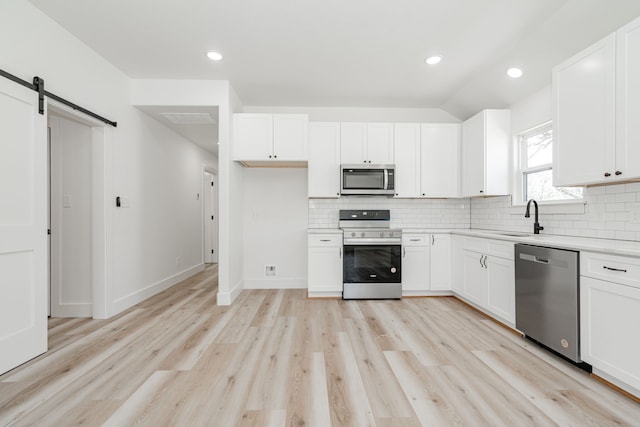 308 Santa Fe, Wolfe City, TX 75496 - kitchen with a barn door, a sink, stainless steel appliances, and backsplash