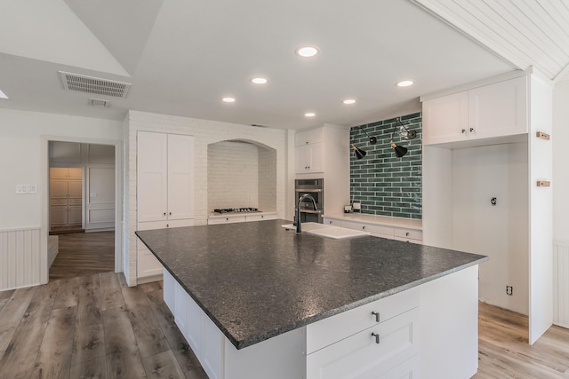 kitchen featuring sink, light hardwood / wood-style floors, a center island with sink, and white cabinets